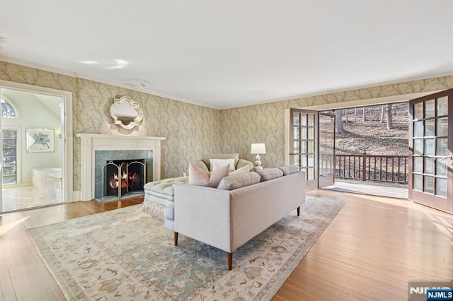 living area with a high end fireplace, wood finished floors, plenty of natural light, and wallpapered walls