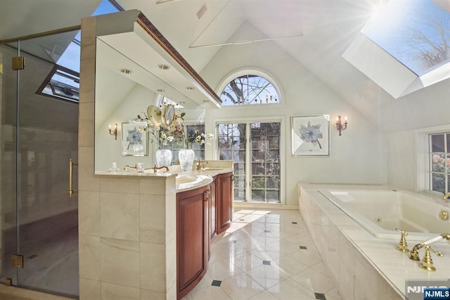 full bath featuring vaulted ceiling with skylight, a jetted tub, a shower stall, and vanity