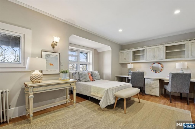 bedroom with recessed lighting, radiator heating unit, ornamental molding, built in study area, and light wood-type flooring