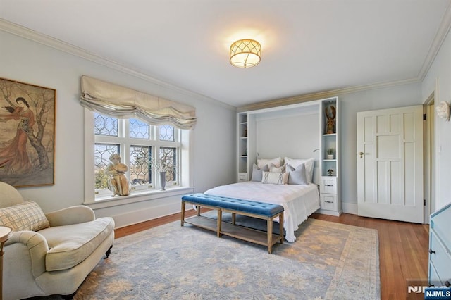 bedroom with baseboards, ornamental molding, and wood finished floors