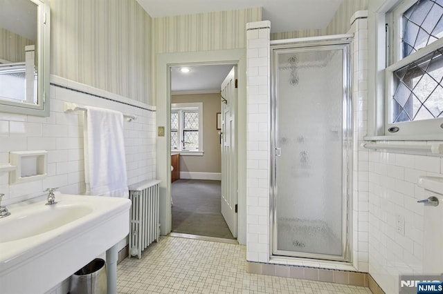 bathroom featuring wallpapered walls, a stall shower, a wainscoted wall, radiator heating unit, and tile walls