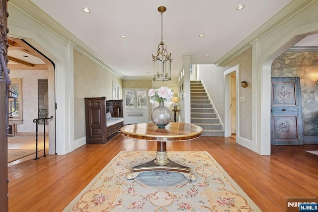 interior space with arched walkways, stairway, wood finished floors, crown molding, and recessed lighting