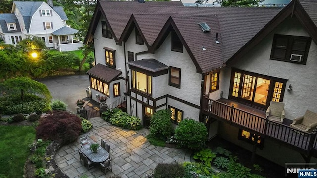 back of house featuring a patio area, roof with shingles, and stucco siding