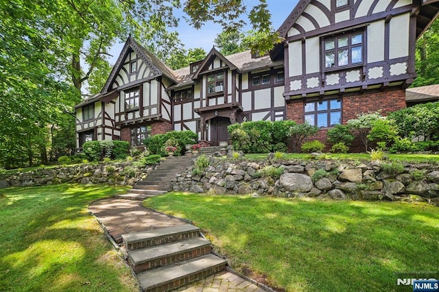 view of front of house featuring a front yard, brick siding, and stucco siding