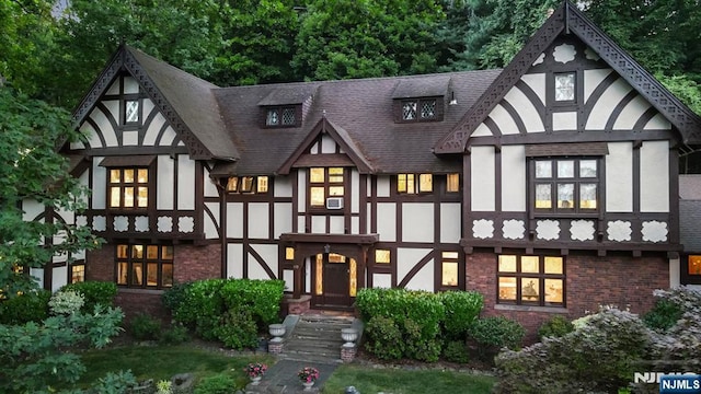 view of front of property featuring brick siding, roof with shingles, and stucco siding