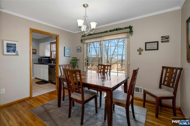 dining room featuring ornamental molding, light wood finished floors, baseboards, and a notable chandelier