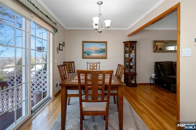 dining space featuring baseboards, light wood finished floors, an inviting chandelier, and crown molding