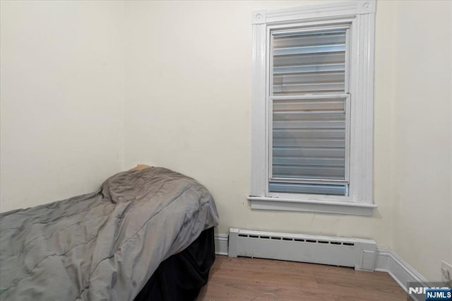 bedroom with a baseboard radiator, baseboards, and wood finished floors