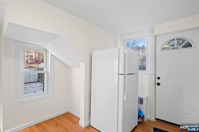 entrance foyer featuring light wood-type flooring, radiator, baseboards, and vaulted ceiling