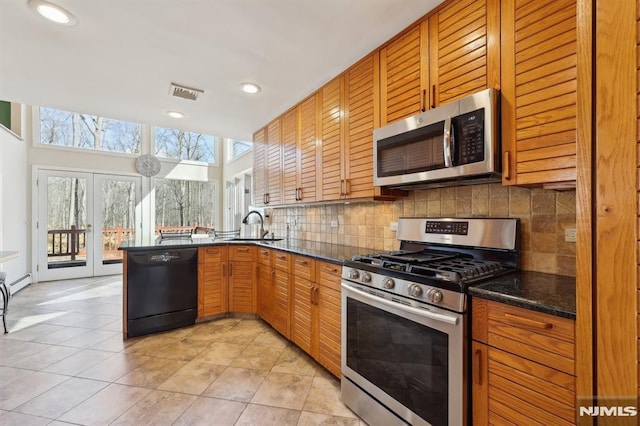 kitchen with visible vents, a peninsula, a sink, decorative backsplash, and stainless steel appliances