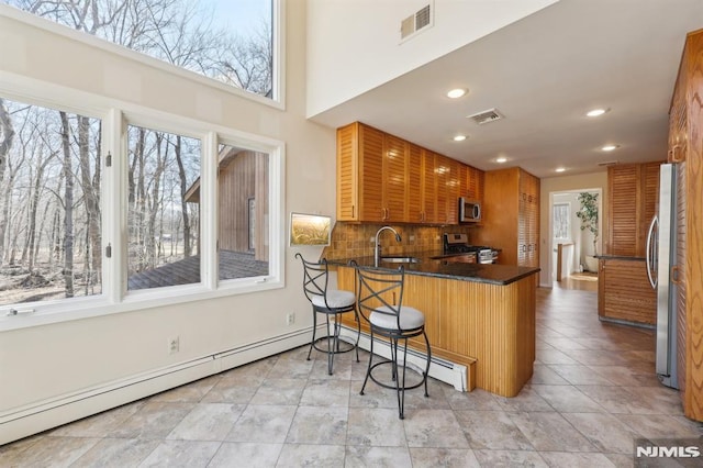 kitchen with visible vents, backsplash, appliances with stainless steel finishes, and a peninsula