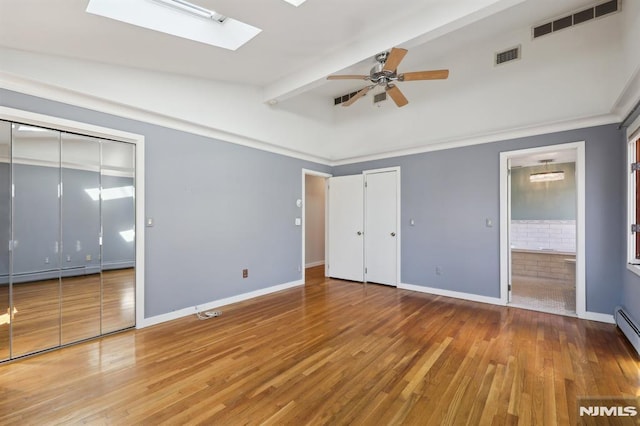 unfurnished bedroom featuring visible vents, a skylight, baseboards, and wood finished floors