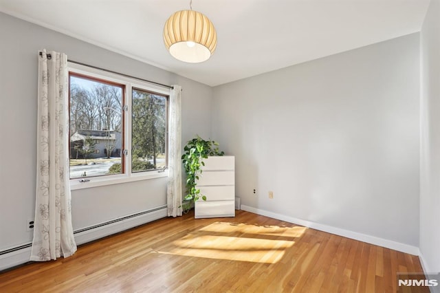 spare room featuring wood finished floors, baseboards, and baseboard heating