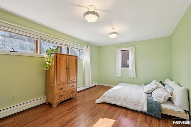 bedroom featuring wood finished floors, baseboards, and baseboard heating