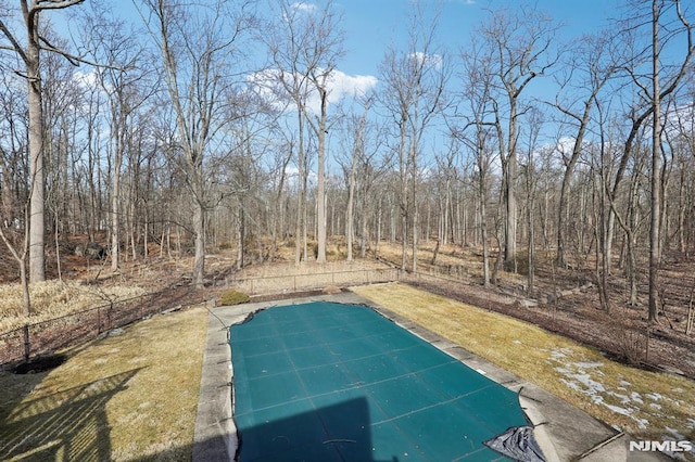 view of swimming pool featuring a yard and fence