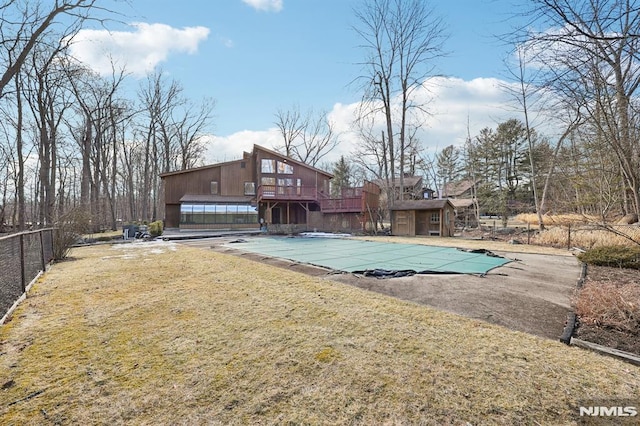 back of property featuring a covered pool, a yard, and fence