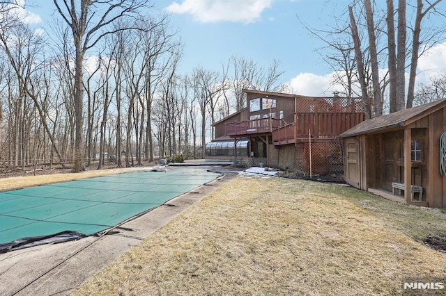 view of swimming pool with a covered pool, a yard, an outbuilding, and a deck