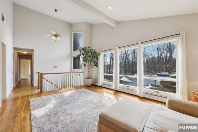 living area featuring wood finished floors, baseboards, beam ceiling, recessed lighting, and an upstairs landing