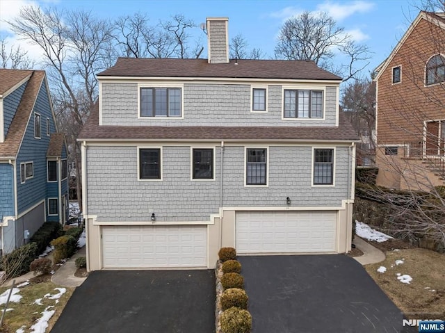 view of front of house featuring driveway, a chimney, and an attached garage