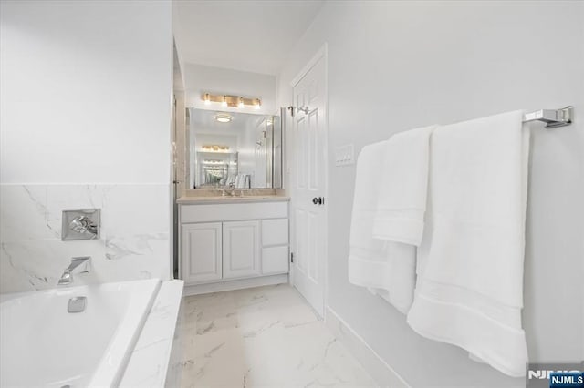 full bathroom with marble finish floor, a garden tub, and vanity