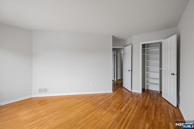 unfurnished bedroom featuring baseboards, a closet, visible vents, and light wood-style floors