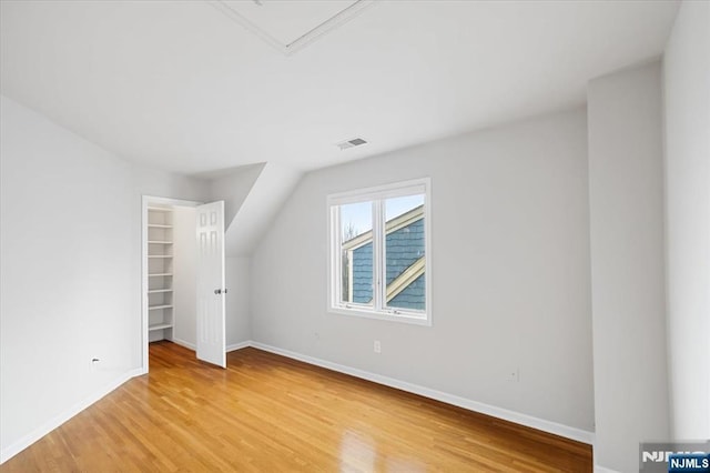 interior space featuring baseboards, visible vents, a spacious closet, light wood-style floors, and a closet