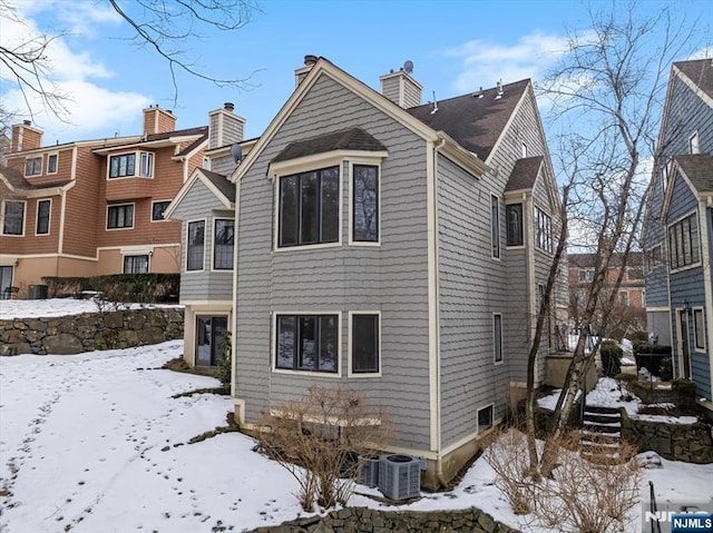 snow covered house with a chimney and cooling unit