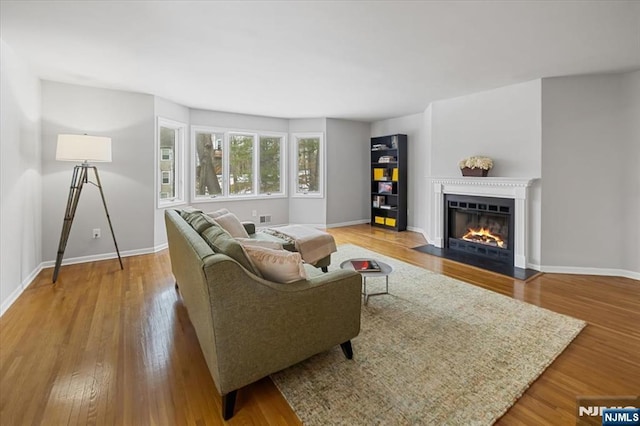 living area with a fireplace with flush hearth, baseboards, and wood finished floors