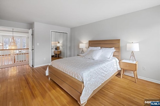 bedroom with light wood-type flooring, baseboards, and a closet