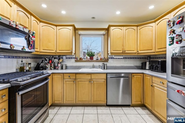 kitchen with light tile patterned floors, decorative backsplash, stainless steel appliances, light countertops, and a sink