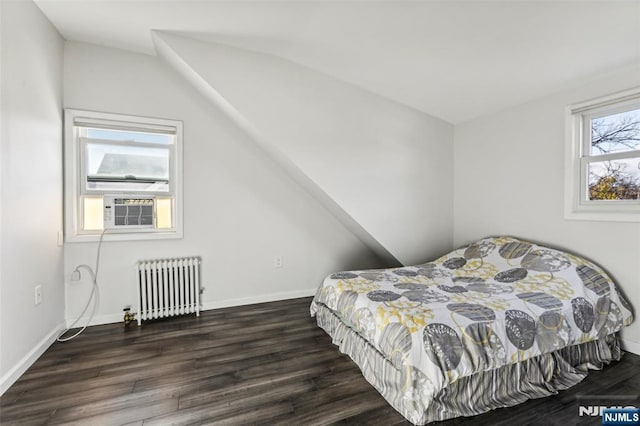 bedroom with radiator, cooling unit, baseboards, and wood finished floors