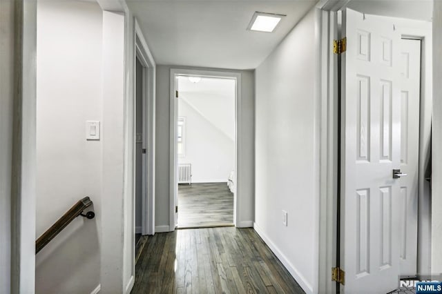 hall with dark wood-style floors, radiator, and baseboards