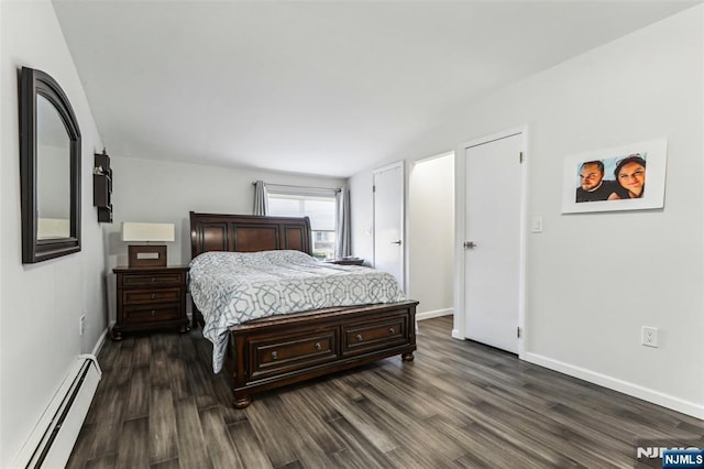 bedroom featuring a baseboard heating unit, dark wood-type flooring, and baseboards