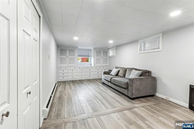 living room with a baseboard heating unit, recessed lighting, light wood-style flooring, and baseboards