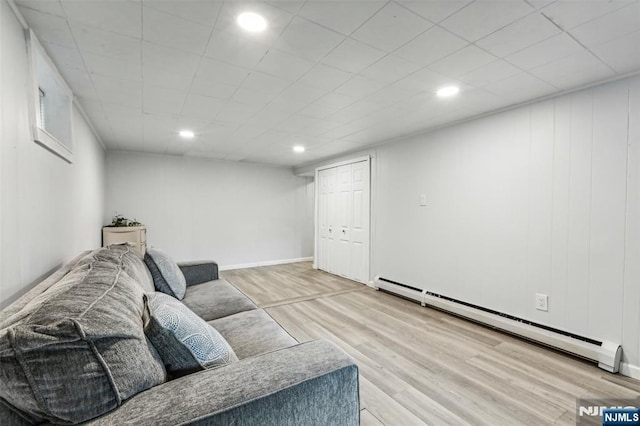 living area with a baseboard heating unit, baseboards, wood finished floors, and recessed lighting