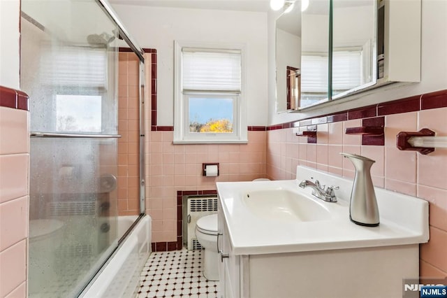 bathroom with tile walls, radiator, toilet, vanity, and tile patterned floors