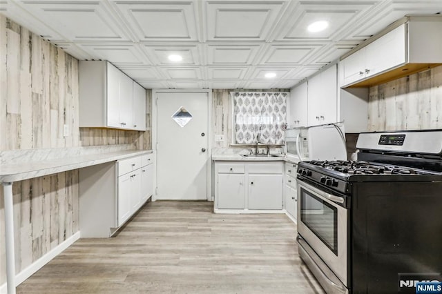 kitchen with gas range, an ornate ceiling, light countertops, white cabinetry, and a sink