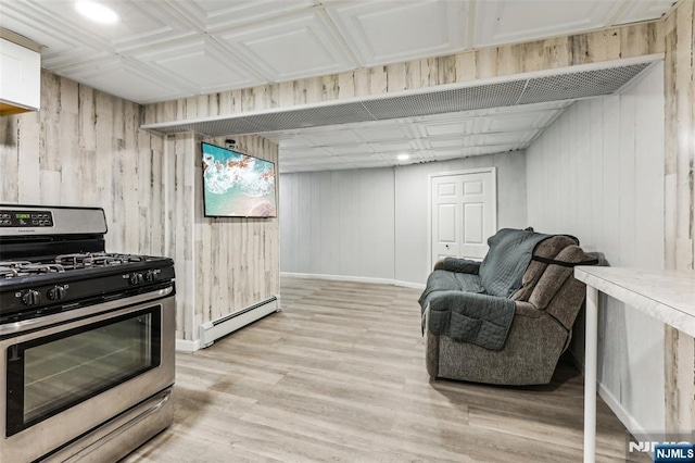 kitchen with a baseboard heating unit, stainless steel gas stove, light wood-style flooring, and baseboards