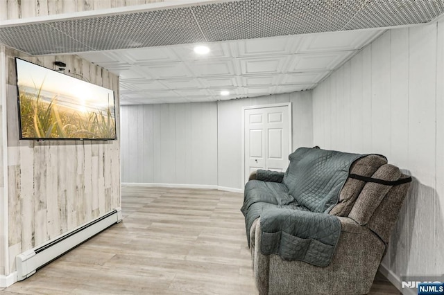 sitting room featuring an ornate ceiling, light wood finished floors, a baseboard radiator, and baseboards