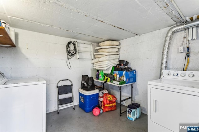 laundry area with concrete block wall and independent washer and dryer