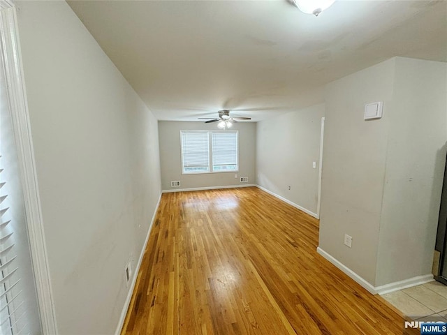 spare room featuring light wood-type flooring, ceiling fan, and baseboards