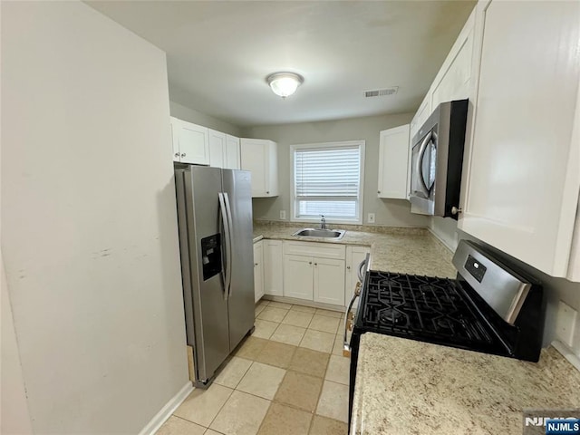 kitchen featuring light tile patterned floors, stainless steel appliances, a sink, visible vents, and white cabinetry