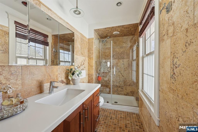 full bathroom with tile walls, decorative backsplash, toilet, a shower stall, and vanity