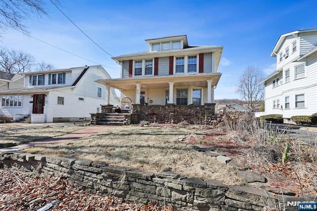 american foursquare style home featuring stone siding and a porch