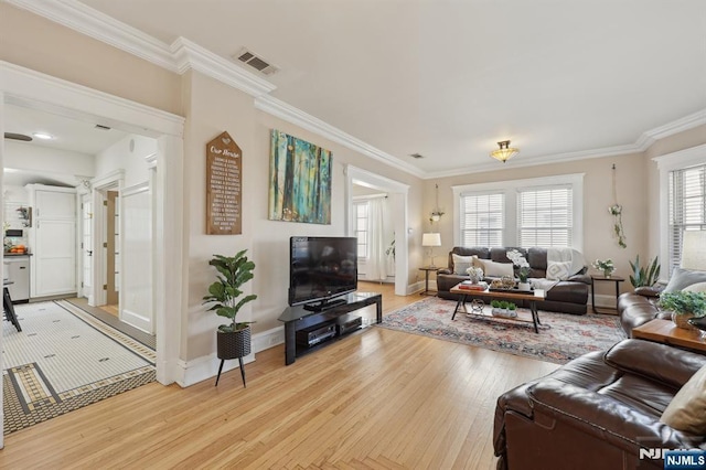 living area featuring light wood-style flooring, visible vents, baseboards, and crown molding