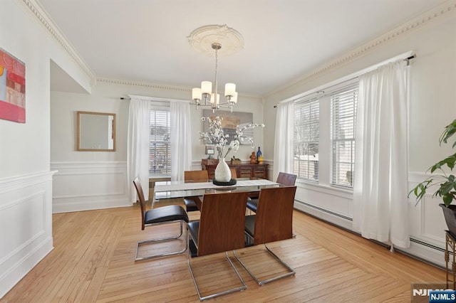 dining area featuring wainscoting, ornamental molding, an inviting chandelier, parquet flooring, and a decorative wall