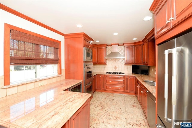 kitchen with tasteful backsplash, wall chimney exhaust hood, appliances with stainless steel finishes, light stone counters, and recessed lighting