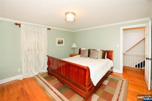 bedroom with baseboards, ornamental molding, and wood finished floors