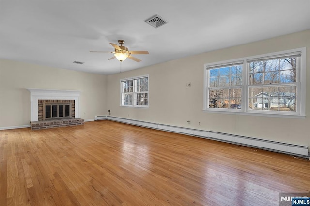 unfurnished living room with light wood-style flooring, visible vents, a ceiling fan, baseboard heating, and a brick fireplace