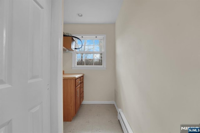 bathroom featuring a baseboard heating unit, tile patterned floors, and baseboards